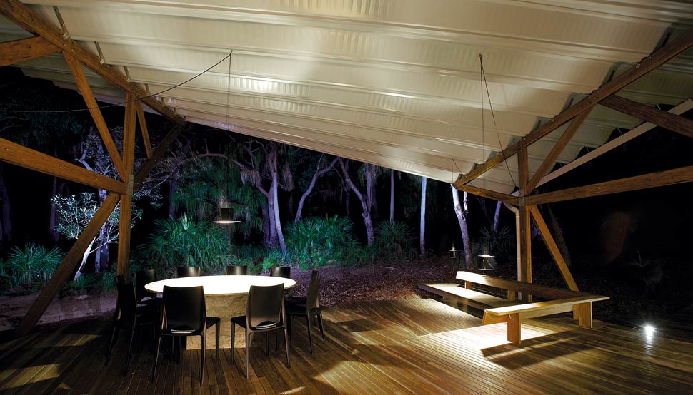 Outdoor living is on a timber deck under the swooping roof.