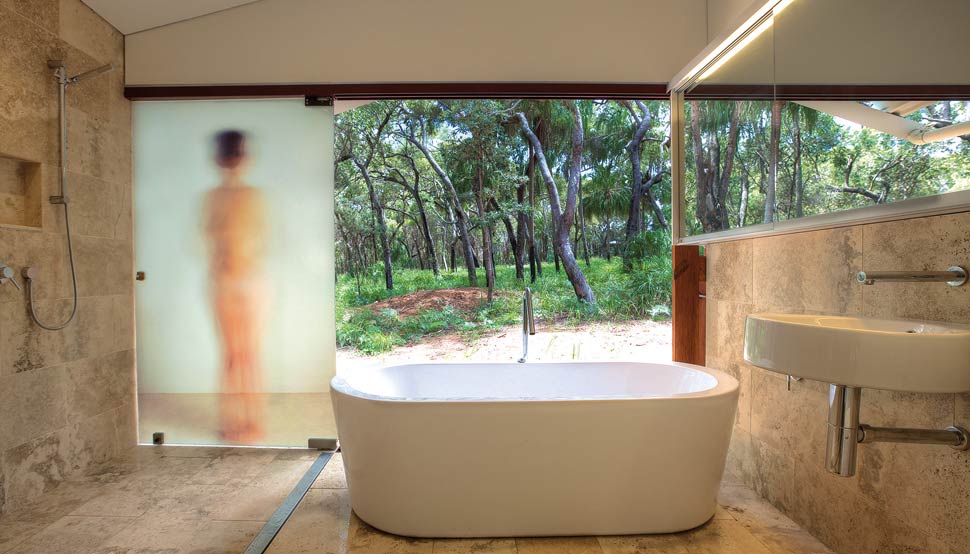 A double layer of doors opens the bathroom wall to the northern sun. A pivoting shower screen uses one of Drew’s photographic portraits for privacy.