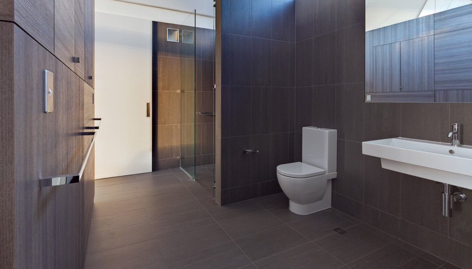 Ribbons of glass that offer views of the sky expand and contract to fill in the spaces beneath the undulating steel roof, as seen here in the master ensuite.