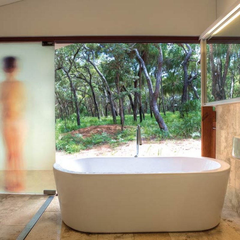 A double layer of doors opens the bathroom wall to the northern sun. A pivoting shower screen uses one of Drew’s photographic portraits for privacy.