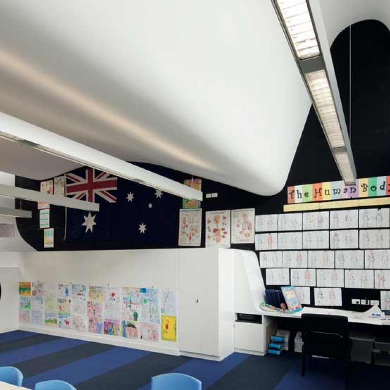 The steel ‘sausage’ extrusion of the Nicholson Street profile creates an unusual roof line and engaging spaces inside, particularly on the upper-level where classrooms with curved ceilings are painted in a vivid blue colour scheme to create a “floating in the clouds” experience for Year 6 students. 